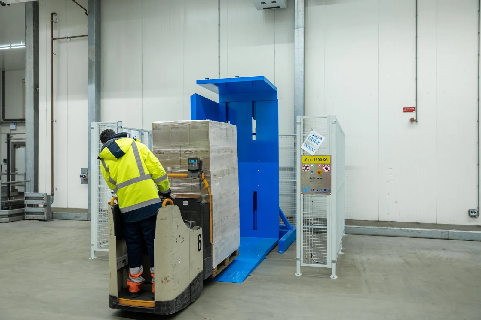 Medewerker rijdt met elektrische pompwagen en pallet de oprit van de palletkantelaar PalletRotator EPT op